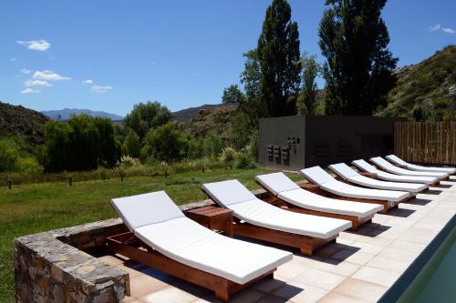 a row of chaise lounge chairs sitting on a patio at Posada del Blanco in Potrerillos