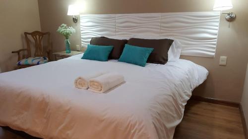 un grande letto bianco con due asciugamani arrotolati di Hotel Las Calas a Paso de los Toros