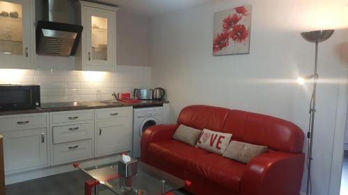 a living room with a red couch in a kitchen at My Glasgow House Bishopbriggs in Bishopbriggs