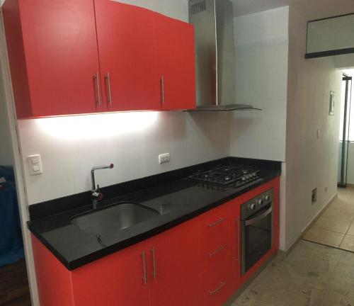 una cocina con armarios rojos y fregadero en Mi casa es su casa, en Lima