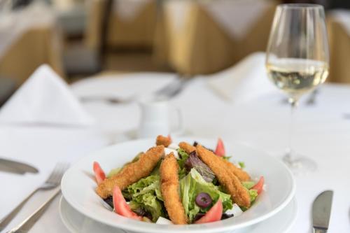 a white plate with a salad and a glass of wine at LP Los Portales Hotel Piura in Piura