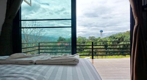 a bedroom with a bed and a large window at Phu Sumphao Valley ภูสำเภา วัลเลย์ รีสอร์ต in Loei