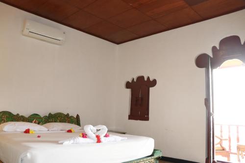 a bedroom with a bed with a cross on the wall at Puri Bunga Beach Cottages in Senggigi 