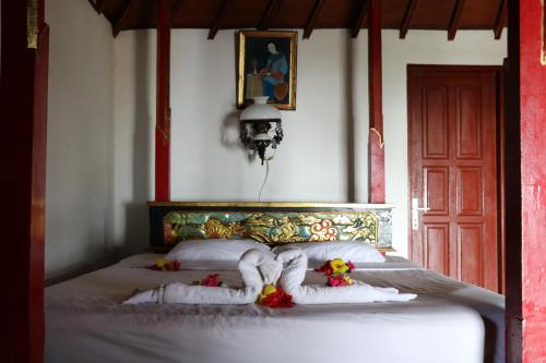 a bedroom with a bed with white sheets and flowers at Puri Bunga Beach Cottages in Senggigi 