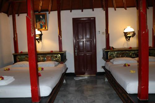 a room with four beds with red posts at Puri Bunga Beach Cottages in Senggigi 