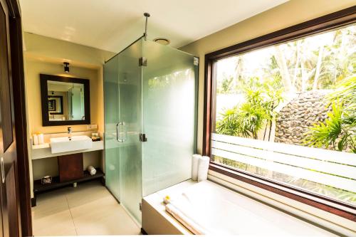 a bathroom with a shower and a sink and a window at Tambua Sands Beach Resort in Korotogo