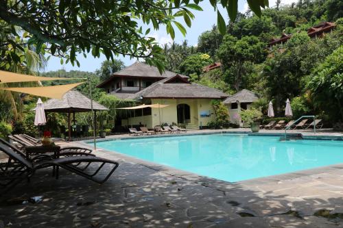 a pool at a resort with chairs and umbrellas at Puri Bunga Beach Cottages in Senggigi 