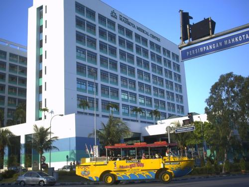 a yellow bus driving down a street in front of a building at Costa Mahkota (Family Homestay) @ Mahkota Melaka in Melaka