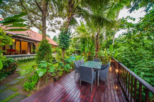 a wooden deck with a table and chairs on it at Luxury 3BR Infinity Jungle View Aashaya Villa Ubud in Ubud