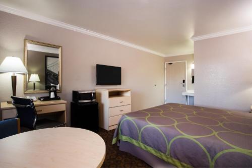 a hotel room with a bed and a desk and a television at Super 8 by Wyndham Vacaville in Vacaville