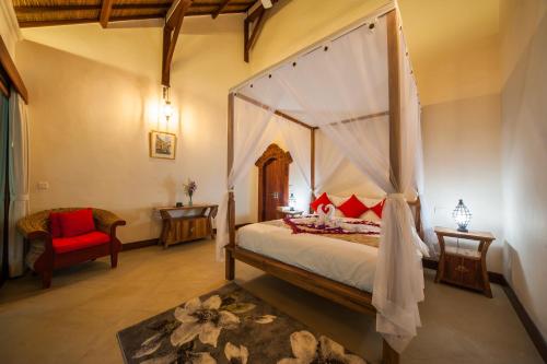 a bedroom with a canopy bed and a red chair at Luxury 3BR Infinity Jungle View Aashaya Villa Ubud in Ubud
