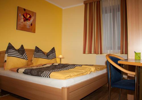 a bedroom with a bed with yellow walls and a table at Frühstückspension Kuzmic in Wartberg