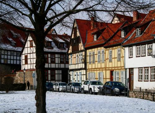 a group of buildings with cars parked on a snowy street at Hotel garni Tilia in Quedlinburg