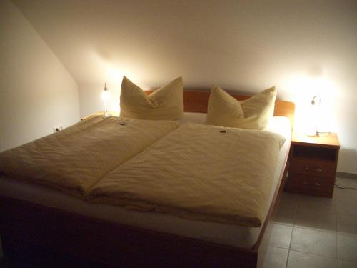 een bed met witte lakens en kussens in een slaapkamer bij Steinbock-Ferienwohnungen in Kolpinsee