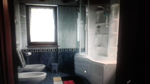 bagno con 2 lavandini, servizi igienici e finestra di Appartamento monteisola mara a Monte Isola