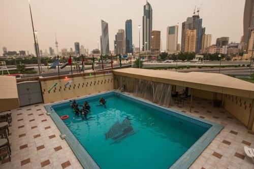 a swimming pool on top of a building with a city at Kuwait Continental Hotel in Kuwait