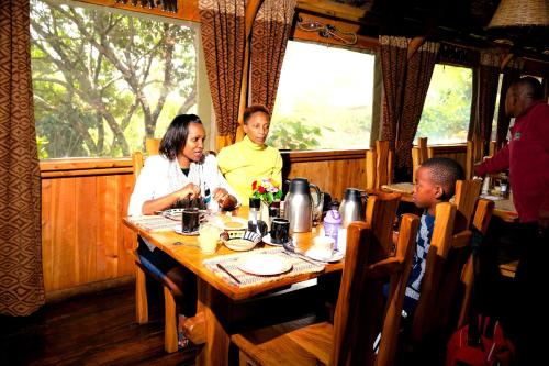 a group of people sitting around a table in a restaurant at Rhino Watch Safarilodge in Mweiga
