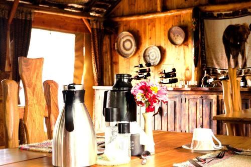 a wooden table with two bottles and a vase with flowers at Rhino Watch Safarilodge in Mweiga