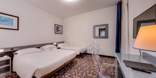 a hotel room with two beds and a desk at Hotel San Giusto in Trieste