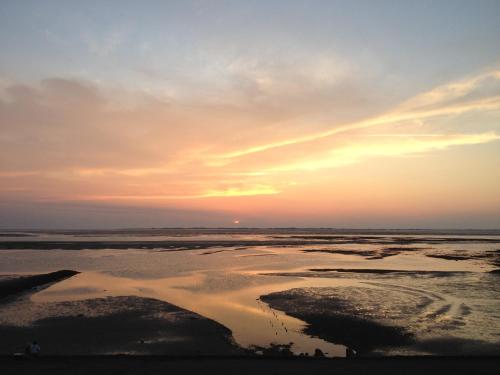 a sunset over a beach with a body of water at Rackmers Hof - Suiten Hotel garni mit Sauna in Oevenum