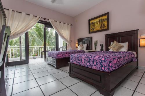 a bedroom with two beds and a balcony at Grace Boutique Resort in Mui Ne