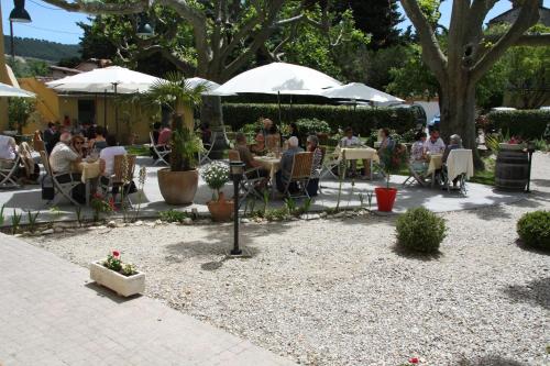 eine Gruppe von Menschen, die an Tischen unter Sonnenschirmen sitzen in der Unterkunft Jac'Soul Restaurant & Chambres d'hotes in Sablet