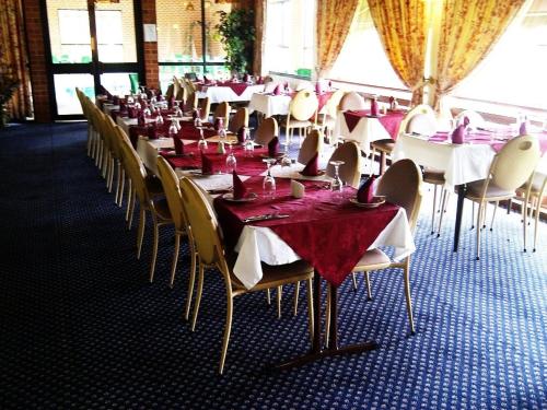 Elsinor Motor Lodge في ولونغونغ: غرفة طعام مع طاولات وكراسي مع مفارش مائدة حمراء