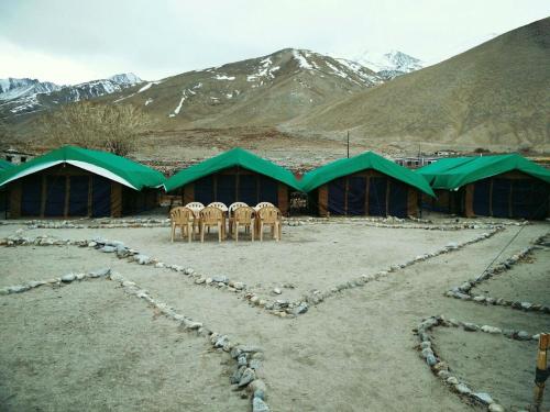 a group of chairs and tents with mountains in the background at Pangong Delight Camps and Cottages in Spangmik