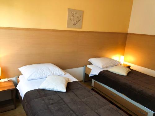 two beds in a room with two lamps on at Smještaj Natalija in Osijek
