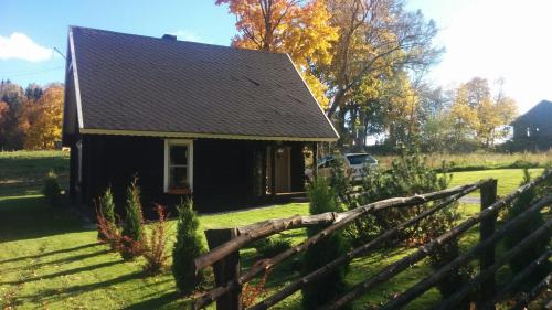 a small black house with a wooden fence at Safari House in Otepää