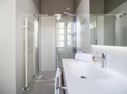 a white bathroom with a sink and a shower at Palazzo Leopoldo Dimora Storica & Spa in Radda in Chianti
