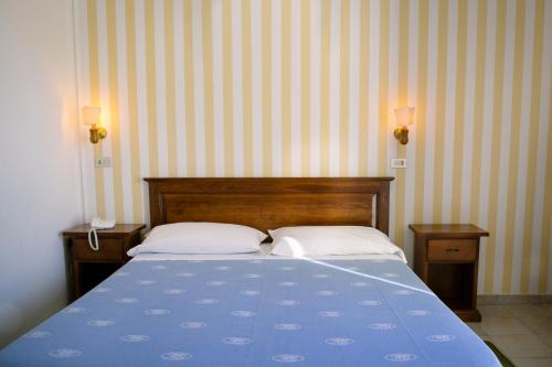 a bedroom with a blue bed with two pillows at Hotel Giardino in Follonica