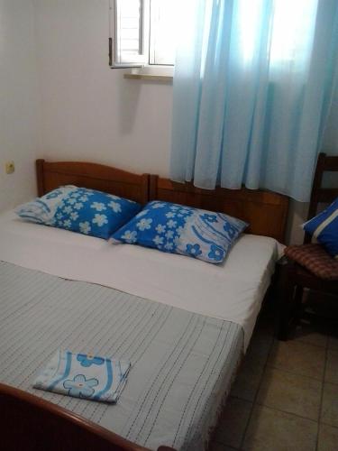 a bedroom with two beds with blue pillows and a window at House Rasohatica Tare in Korčula