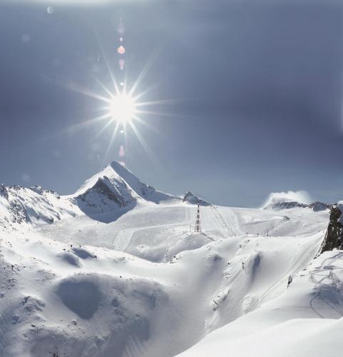 a snow covered mountain with the sun in the sky at Hotel Quehenberger in Maishofen