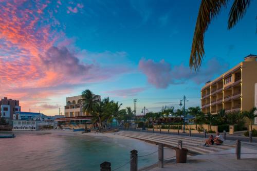 a sunset over a beach with buildings and palm trees at Yellow Bird Hotel in Christ Church