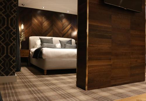 a bedroom with a white bed and a wooden wall at Heritage Park Pontypridd, Trademark Collection by Wyndham in Pontypridd