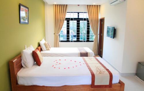 a bedroom with two beds and a window at Melody Boutique Villa Hoi An in Hoi An