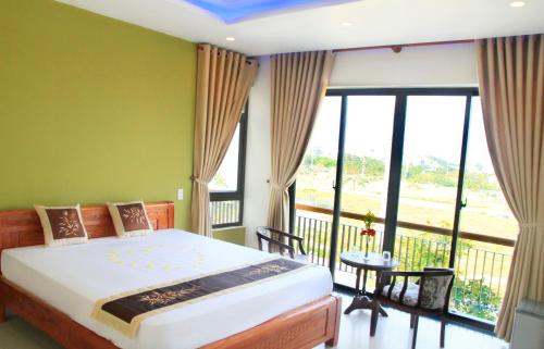 a bedroom with a large bed and a balcony at Melody Boutique Villa Hoi An in Hoi An