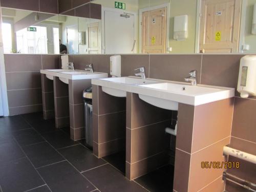 a public bathroom with three sinks and mirrors at Uppsala City Hostel in Uppsala