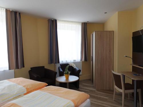 una camera d'albergo con letto, sedia e tavolo di Wolthusen a Emden