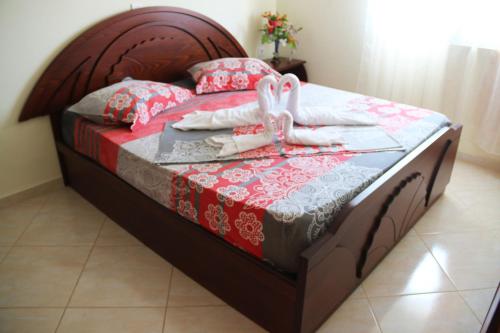 een bed met een houten hoofdeinde en handdoeken bij Tarace sea view apartment in Sarandë