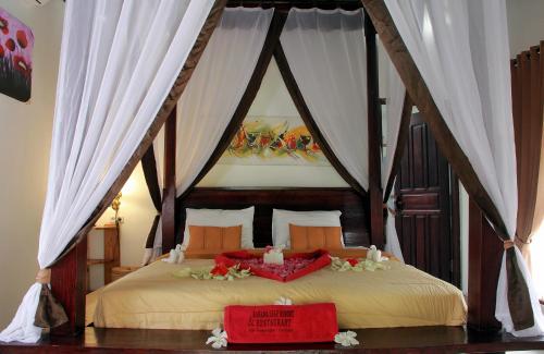 ein Schlafzimmer mit einem Himmelbett mit Blumen darauf in der Unterkunft Banana Leaf Resort in Gili Trawangan