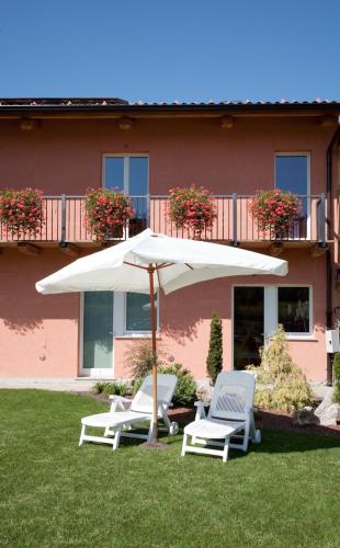 two chairs and an umbrella in the grass in front of a building at Affittacamere Il Torchio in Pianfei