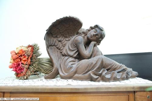 a statue of an angel sitting on a table with flowers at Gästehaus Waldrand Garni in Wiesing