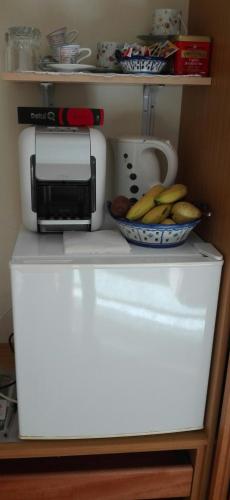 a microwave and a bowl of bananas on a refrigerator at Quarto/Suite de Charme in Viana do Castelo