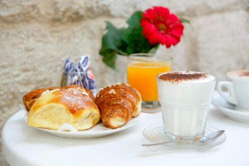 un tavolo con colazione a base di cornetti e succo d'arancia di 3 Archi B&B a Trani