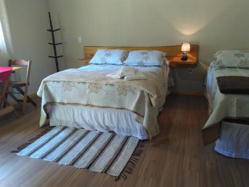 a bedroom with a bed and a wooden floor at Chalés do Pardal in Visconde De Maua
