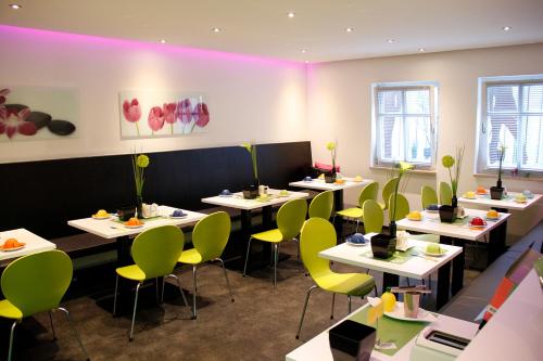 a restaurant with white tables and green chairs at Pension Vicus in Passau