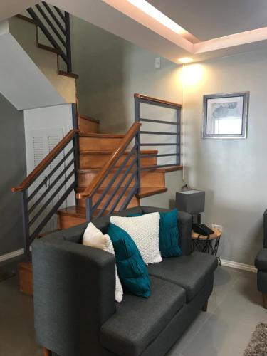 a living room with a couch and a staircase at Hillary Timog Park Homes in Angeles