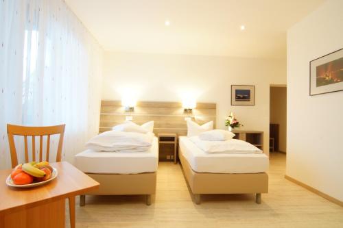 a hotel room with two beds and a table with a bowl of fruit at Hotel Spitzenpfeil in Michelau